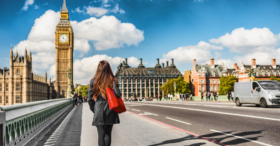 A woman facing away from the camera crosses the bridge walking towards Big Ben in London.